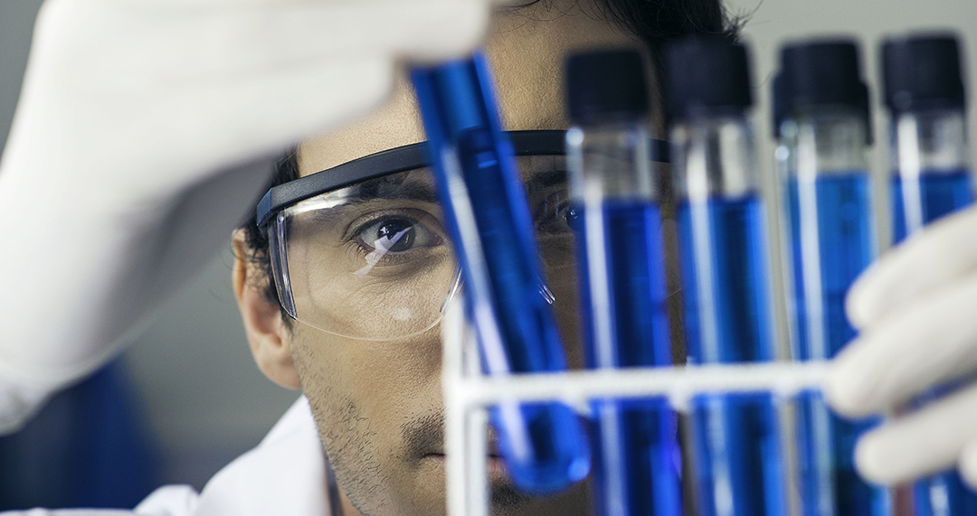 Researcher scrutinizing test tubes in laboratory --- Image by © Frederic Cirou/PhotoAlto/Corbis